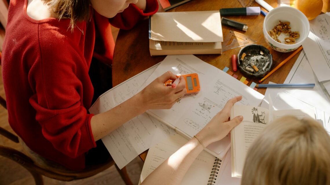 girl in red long sleeve shirt writing on white paper
