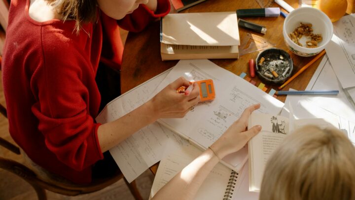girl in red long sleeve shirt writing on white paper