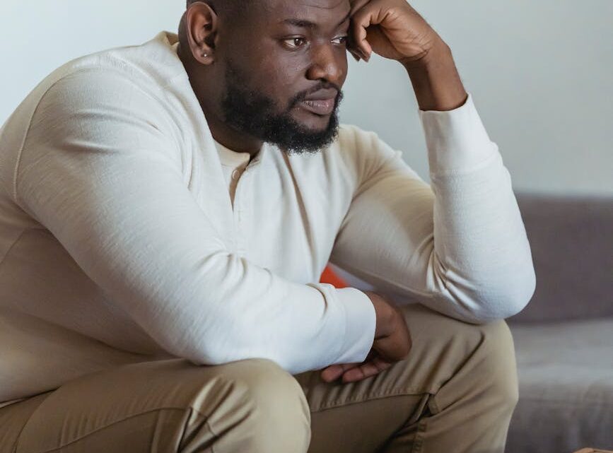 frustrate black man sitting near laptop and thinking